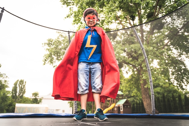 Kind trägt Superheldenkostüme und hat Spaß im Freien