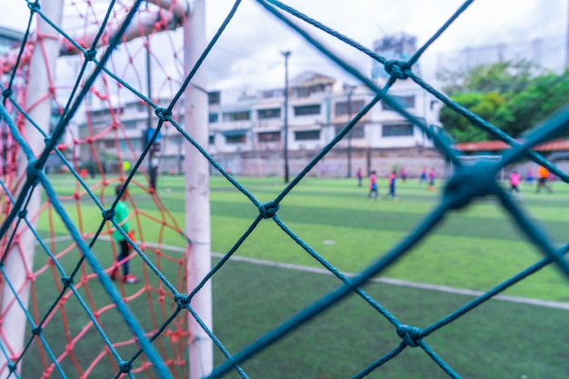 Kind trainiert Fußball Fußball in unscharfem Hintergrund hinter dem Netz