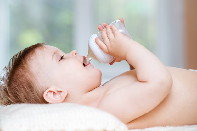 Kind trinkt Kompott aus einer Flasche zu Hause