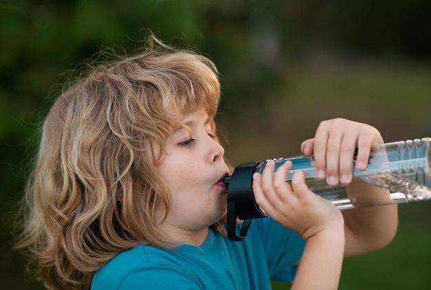 Foto kind trinkt wasser im freien nahaufnahme porträt eines jungen, der wasser aus einer flasche im garten trinkt