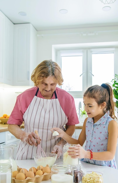 Kind und Großmutter in der Küche backen bereitet den Teig in der Küche vor Selektiver Fokus