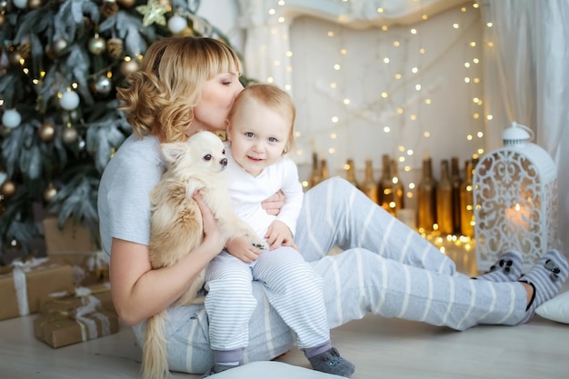 Kind und Mutter im hellen Pyjama auf dem Hintergrund eines Weihnachtsbaums.
