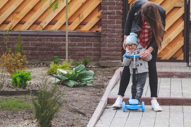 Kind und Mutter spielen draußen mit dem Roller