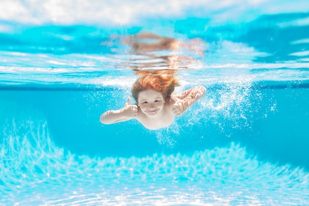 Kind unter Wasser schwimmen im Schwimmbad Süßer Junge, der im Pool unter Wasser schwimmt