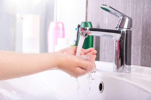 Kind wäscht Hände mit Seife unter dem Wasserhahn mit Wasser