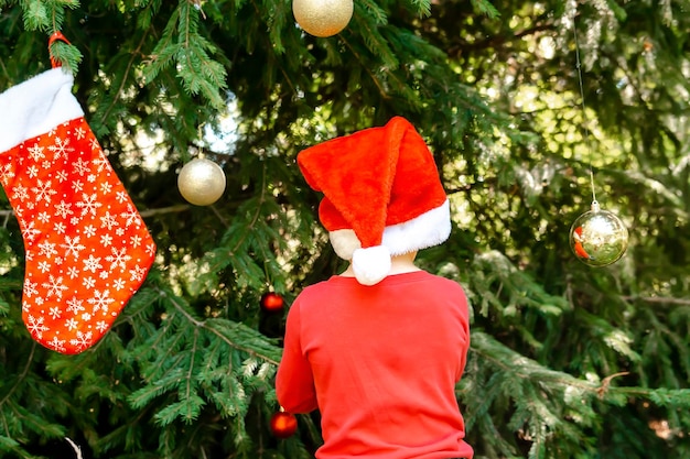 Foto kind wartet auf weihnachten im wald im juli lieber kleiner junge schmückt im sommer im hinterhof den tannen im winter festliche feiertage familienmitglieder frohe weihnachtsnacht neues jahr glückliche feiertage