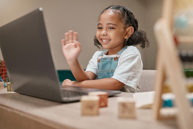 Kind winkt oder Laptop-Videoanruf für Homeschool-Bildung, e-Lernunterstützung oder Lockdown-Klasse im Haus oder Wohnzimmer zu Hause Lächeln Sie glücklich oder grüßen Sie die Handgeste für Schüler im Technologie-Webinar