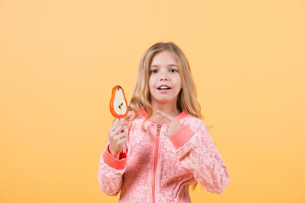 Kind zeigt mit dem Finger auf Süßigkeiten am Stock, Essen. Kindermädchen mit Lutscher, Kindheit.