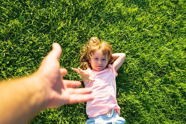 Kind zieht Vaterhand. Folge mir, Hand in Hand an einem strahlend sonnigen Tag. Kind, das die Hand des Mannes hält und ihn auf die Natur im Freien führt.