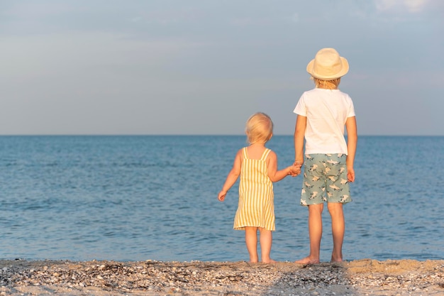 Kinder am Meer Rückansicht Bruder hält seine kleine Schwester an der Hand