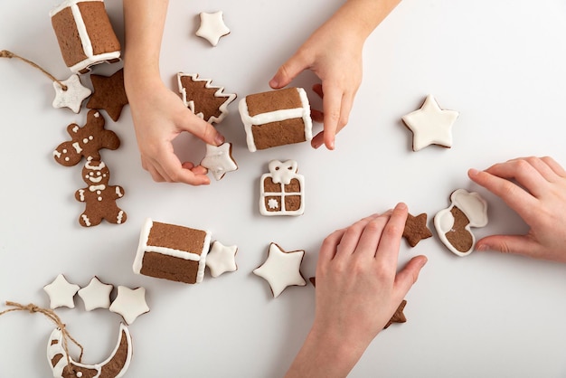 Kinder backen Lebkuchen. Zuckerglasierte Lebkuchen und Kinderhände auf weißem Hintergrund, Ansicht von oben.