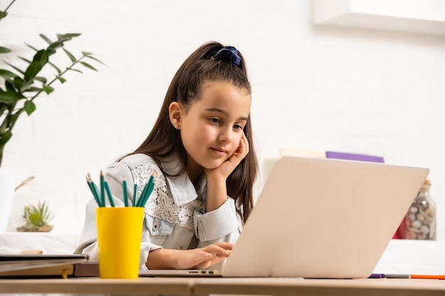 Kinder-, Bildungs- und Fernlernkonzept - kleines Studentenmädchen mit Laptop-Computer zu Hause