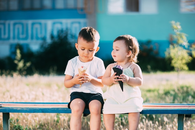 Kinder, Bruder und Schwester auf der Bank Eis essen ist sehr lustig und süß