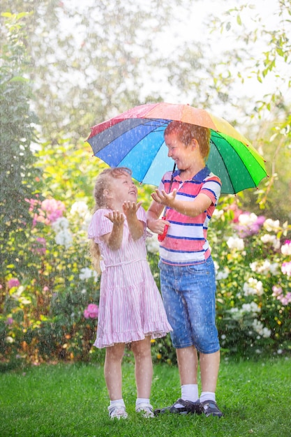 Kinder Bruder und Schwester stehen mit Regenschirm im Regen