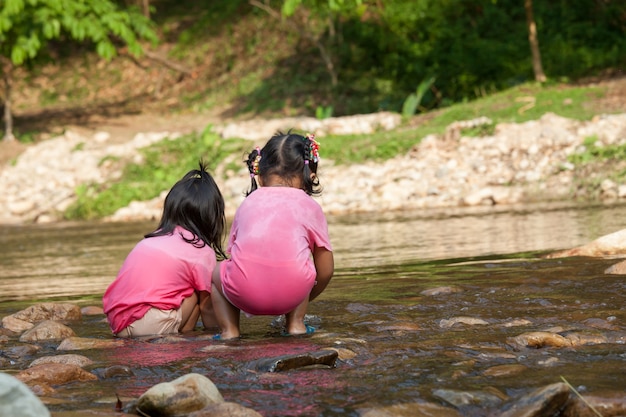 Kinder des Kindes zwei, die Spaß haben, im Wasserfall zusammen in der Sommerzeit zu spielen