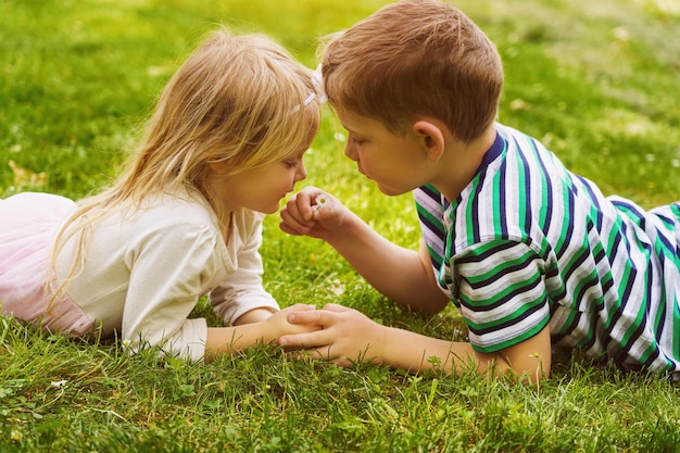 Kinder, die auf dem grünen Gras im Park liegen Die Interaktion o