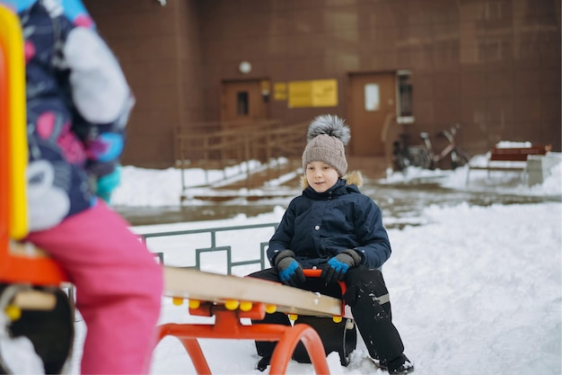 Kinder, die auf dem Meer schaukeln, sahen im Winter auf dem Spielplatz