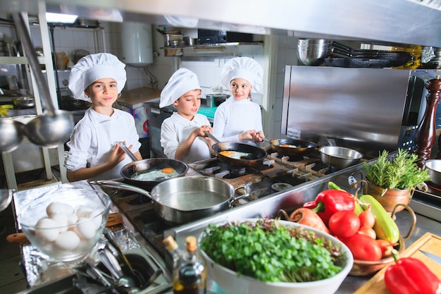 Kinder, die das Mittagessen in einer Restaurantküche kochen.