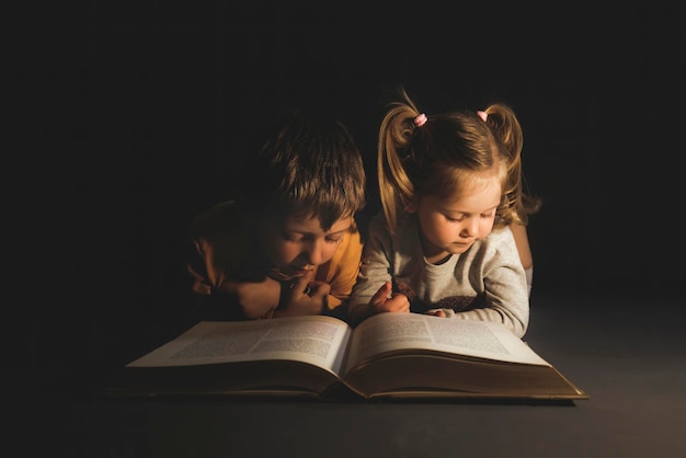 Kinder, die ein Buch lesend liegen