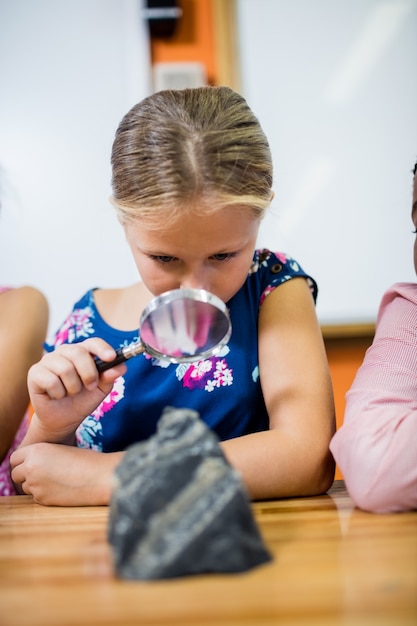 Kinder, die Fossilien mit einer Lupe schauen