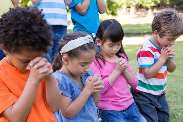 Kinder, die ihre Gebete im Park sagen