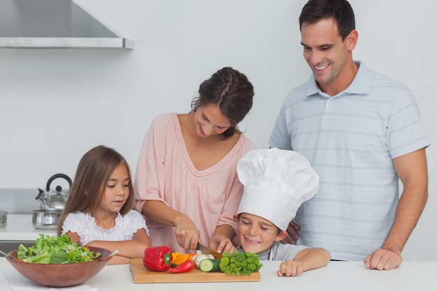 Kinder, die ihre Mutter betrachten, die Gemüse schneidet