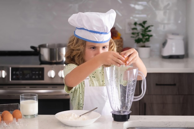 Kinder, die in der Küche kochen Lustiger Kinderchef kochen in der Küche Chef-Kind-Junge, der gesundes Essen macht Porträt des kleinen Kindes in Kochmütze