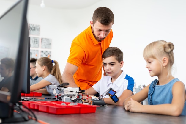 Kinder, die mit dem Lehrer an ihrem Roboterbildungsprojekt arbeiten