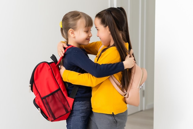 Kinder, die mit Rucksäcken zur Schule gehen, schickes Mädchenkonzept.