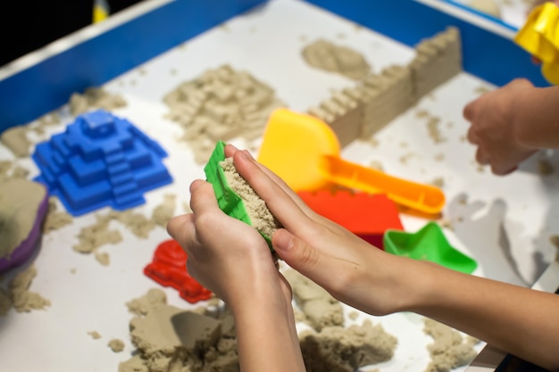 Kinder, die Plastikformspielwaren mit Sand auf Sandkasten spielen.