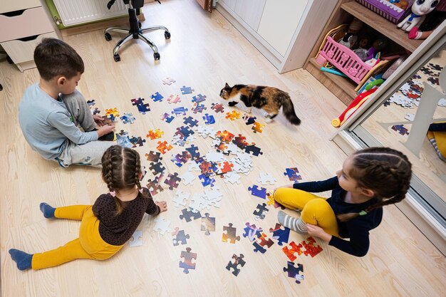 Kinder, die Puzzleteile in einem Kinderzimmer auf dem Boden zu Hause verbinden Lustige Freizeitaktivitäten für die Familie