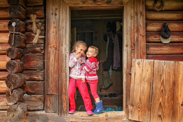 Kinder, die sich während der Sommerferien vor der Haustür des alten Holzhauses ausruhen, umweltfreundliches Reisekonzept