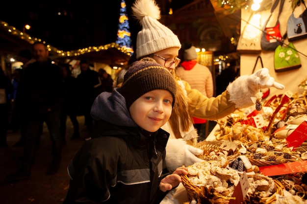 Kinder, die Souvenir auf dem Weihnachtsmarkt auswählen Familienwinterurlaub