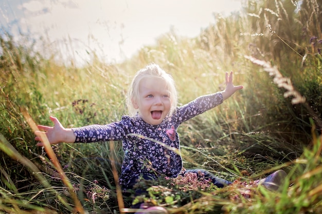 Kinder, die Spaß im grünen Gras mit Blumen auf der Wiese haben, goldener Sonnenuntergang im Sommer