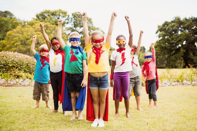 Kinder, die Superheldkostümstellung tragen