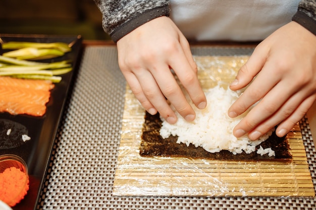 Kinder, die Sushi im Bildungs- und Unterhaltungskonzept der Meisterklasse für Kinder zubereiten