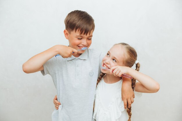 Kinder ein Junge und ein Mädchen putzen ihre Zähne und lachen isoliert auf weißem Hintergrund Kinderzahnheilkunde Hygiene und Reinigung der Zähne