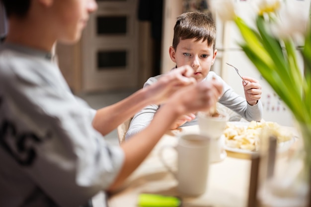 Kinder essen Obst und Desserts trinken Tee zu Hause in der Abendküche Schokolade am Stiel zum Schmelzen