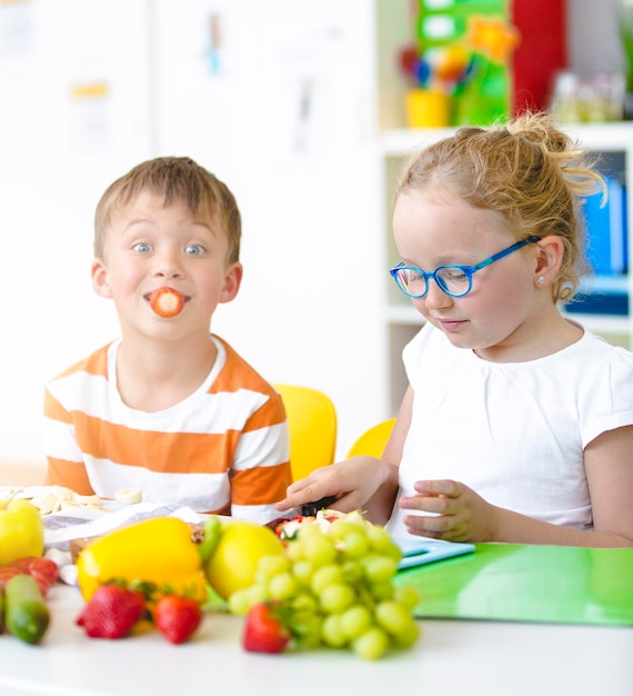 Foto kinder essen, während sie in der schule auf dem tisch sitzen