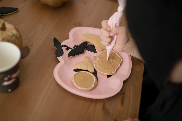 Kinder färben Lebkuchenplätzchen für Halloween.