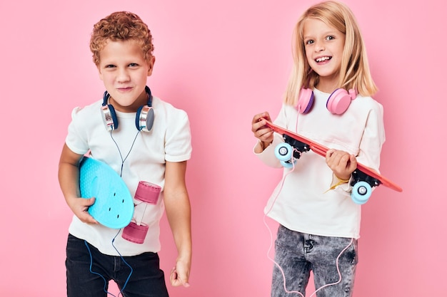 Kinder fahren Skateboard Skateboards in den Händen der Unterhaltung rosa Hintergrundfarbe