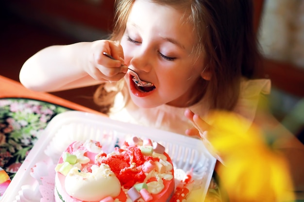 Kinder feiern in Mützen Geburtstag mit Kuchen und Luftballons zu Hause.