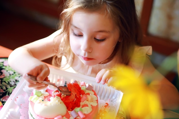 Kinder feiern in Mützen Geburtstag mit Kuchen und Luftballons zu Hause.