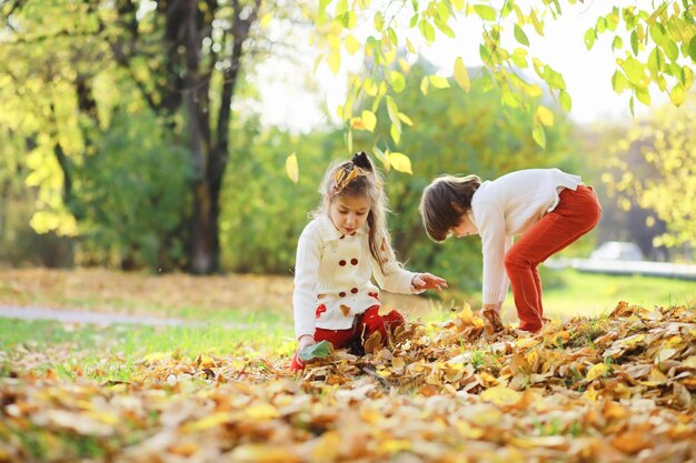 Kinder für einen Spaziergang im Herbstpark Laubfall im Park Familie Herbstglück