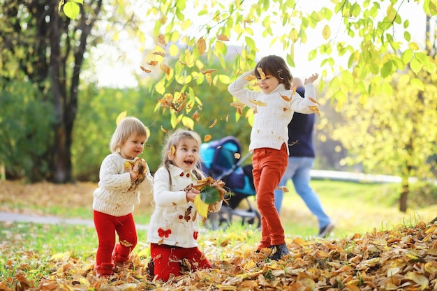 Kinder für einen Spaziergang im Herbstpark Laubfall im Park Familie Herbstglück