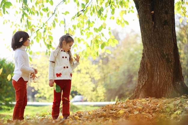 Kinder für einen Spaziergang im Herbstpark Laubfall im Park Familie Herbstglück