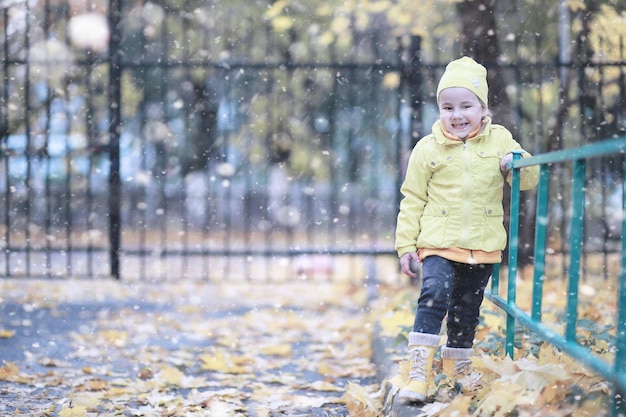 Kinder gehen im ersten Schnee des Parks spazieren