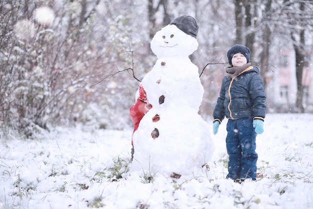 Kinder gehen im ersten Schnee des Parks spazieren