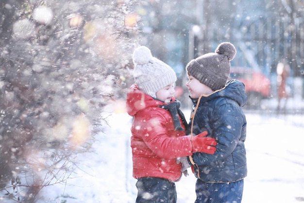 Kinder gehen im ersten Schnee des Parks spazieren