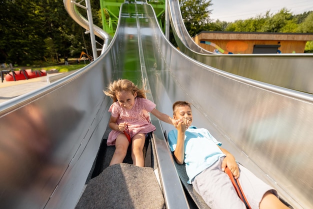 Foto kinder gehen im vergnügungspark eine kinderrutsche hinunter.